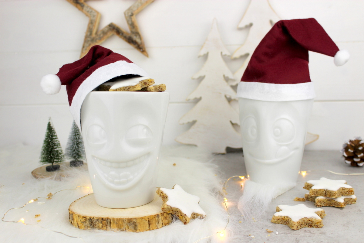 lustige Tassen mit Weihnachtsmannmützen gefüllt mit Zimtsternen