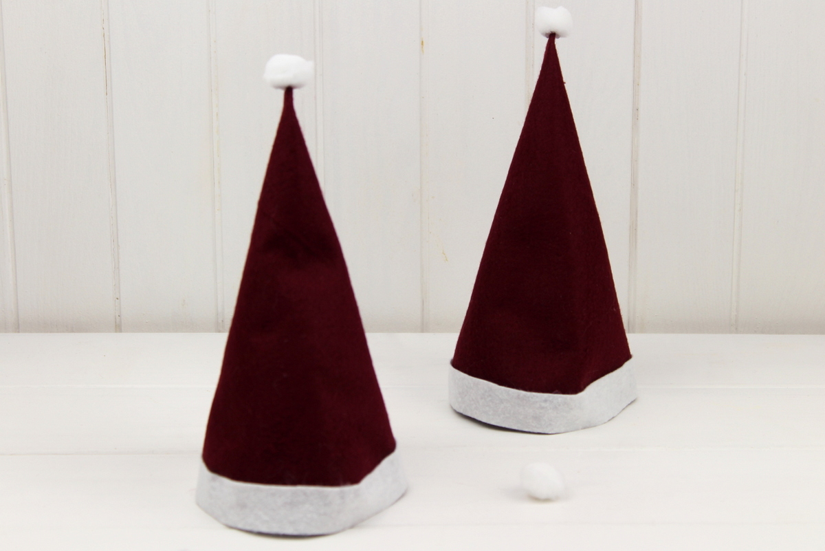 lustige Tassen mit Weihnachtsmannmützen gefüllt mit Zimtsternen