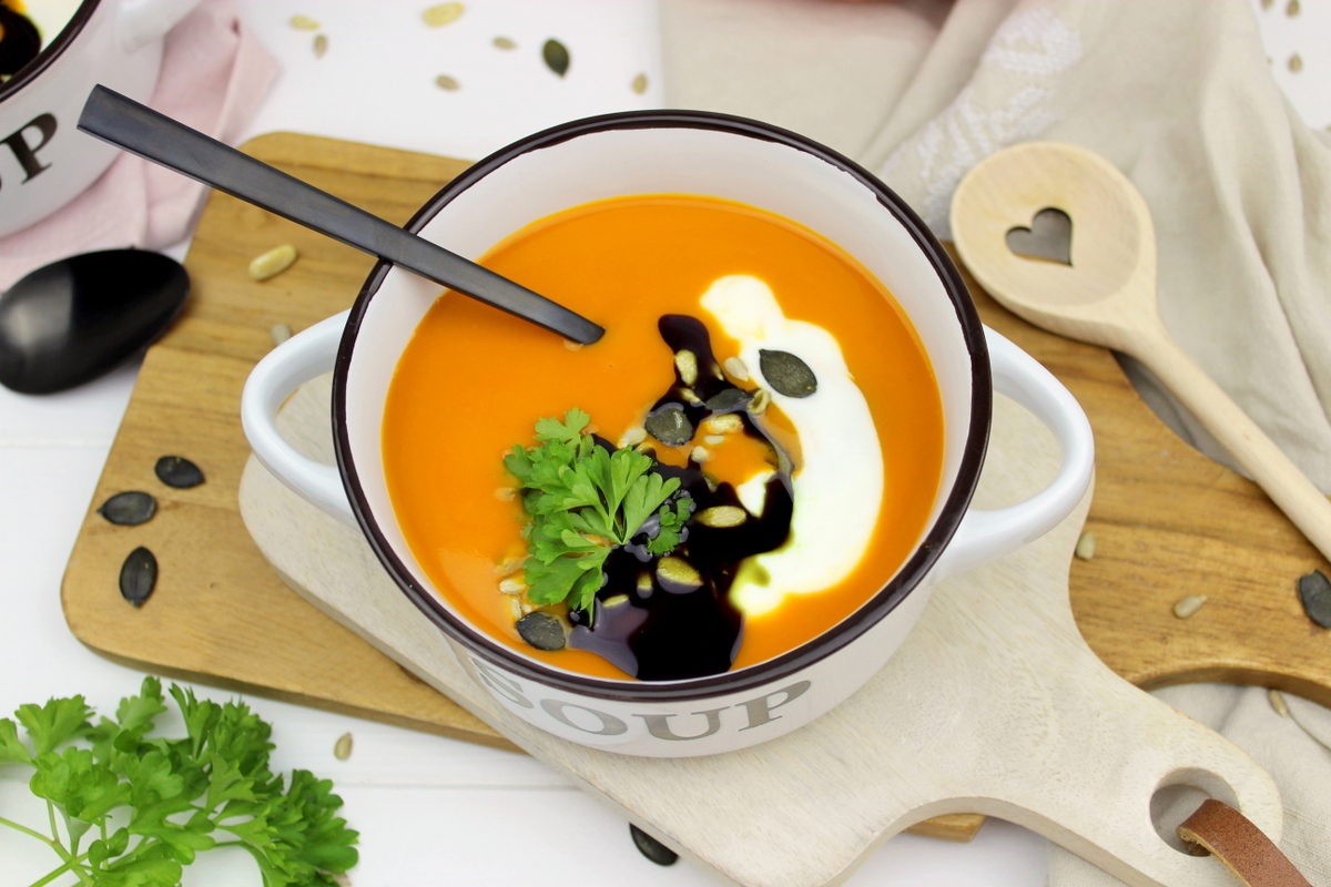 Kürbissuppe mit Hokkaido, Möhren und Kokosmilch serviert mit Petersilie, Kürbiskernen und Kürbisöl