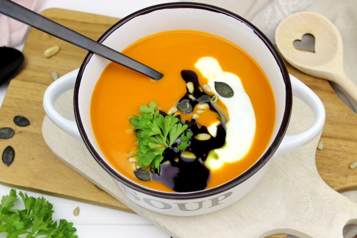 Kürbissuppe mit Hokkaido, Möhren und Kokosmilch serviert mit Petersilie, Kürbiskernen und Kürbisöl
