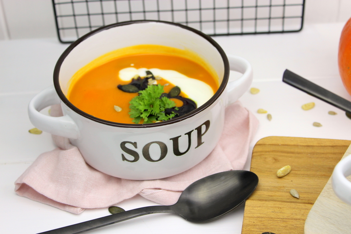 Kürbissuppe mit Hokkaido, Möhren und Kokosmilch serviert mit Petersilie, Kürbiskernen und Kürbisöl